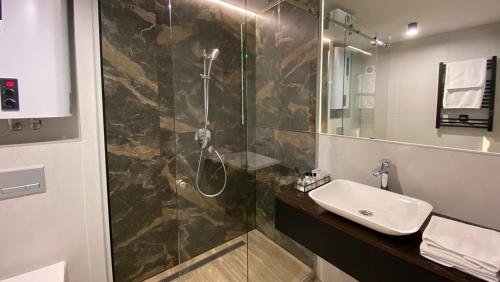 a bathroom with a shower with a sink and a mirror at Optima Collection Kamianske in Kamianske