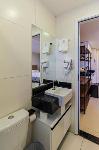 a bathroom with a sink and a toilet and a mirror at Home Studio in Sobral