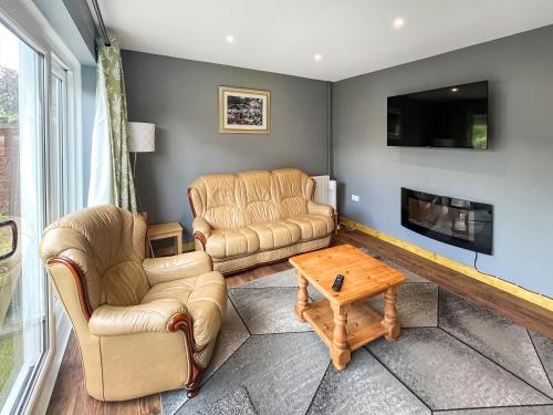 a living room with two couches and a tv at Orcadians in Sellindge
