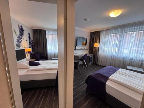 a hotel room with two beds and a desk at Garten-Hotel Ponick in Cologne