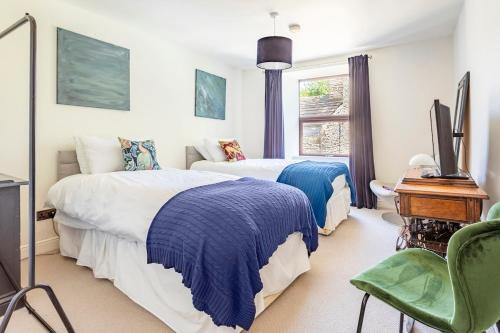 a bedroom with two beds and a desk and a window at Rose Cottage. Family home on the river in Hawes