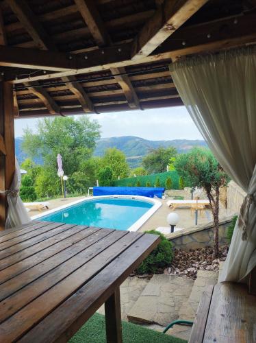 a patio with a wooden table and a swimming pool at Etno selo Milanovic - Nonac in Kuršumlija