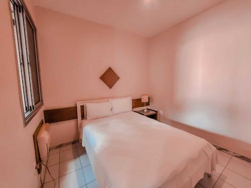 a small bedroom with a white bed and a window at Pampulha Flat in Belo Horizonte
