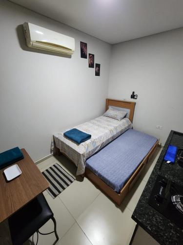 a small bedroom with a bed and a table at Studio Aconchegante in Lins