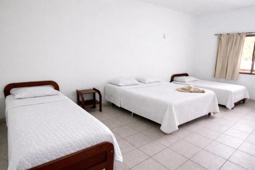 a bedroom with two beds and a table and a window at Garden Hotel e Eventos in Benevides