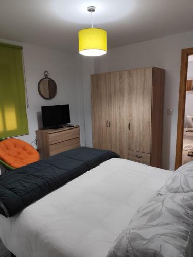 a bedroom with a large white bed and a television at Reyes in Monachil