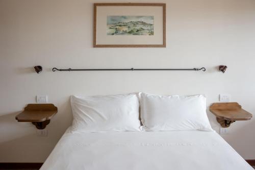 a bedroom with a white bed with two side tables at Semivaganti Agritur in Candelara