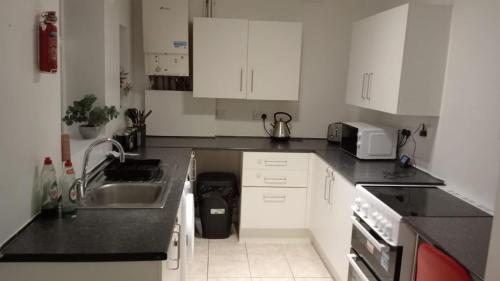 a kitchen with white cabinets and a sink and appliances at ThinkGlobal Properties Ltd in Stoke on Trent