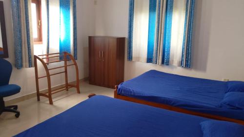 a bedroom with two beds and a chair and windows at Spacious 4BR Green Court Villa for 8-10 Guests AC & Hot Water Thalawathugoda in Talawatugoda