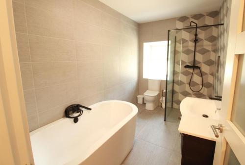 a bathroom with a bath tub and a toilet at The Old Post Office Holiday Home, Dunmore in Galway