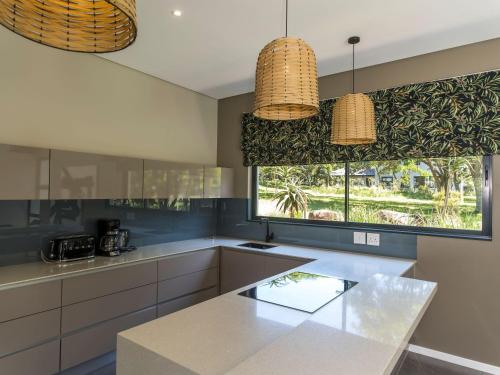 a kitchen with white cabinets and a large window at Luxury Villa Rainbow, Eden Rock Estate, Pennington in Pennington