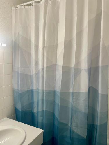 a bathroom with a blue and white shower curtain at Studio à 2 pas de la plage! in Hossegor