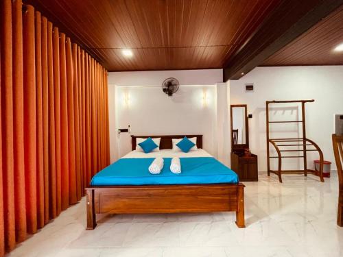a bedroom with a blue bed with orange curtains at Vihen Homestay in Dickwella