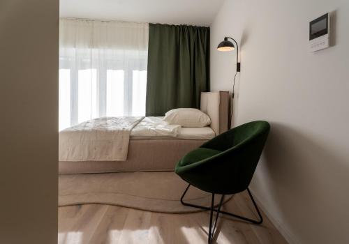 a bedroom with a bed and a green chair at BLI One in Vilsbiburg