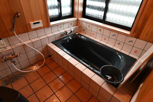 a bathroom with a black tub and a toilet at 森ノ間 大谷荘 in Myoko