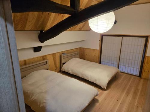 two beds in a room with wood floors and a ceiling at 森ノ間 大谷荘 in Myoko