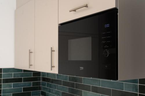 a microwave in a kitchen with blue tile at BLI One in Vilsbiburg