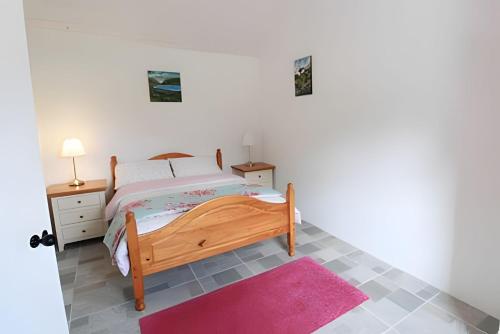 a bedroom with a bed and a pink rug at Historic Louisburgh Farm Cottage in Louisburgh