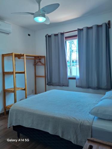 a bedroom with a bed with a ceiling fan and a window at Casa em Prado bahia in Prado