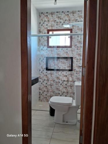 a bathroom with a toilet and a brick wall at Casa em Prado bahia in Prado