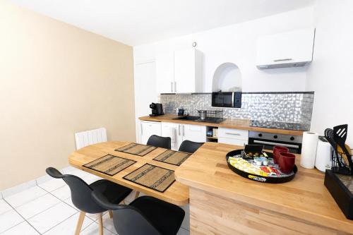 a kitchen with a wooden table and some chairs at La Perle de la Baie - Plages à pied & Hyper centre in Pornichet