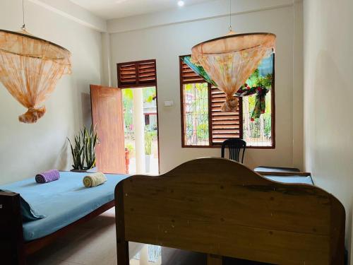 a bedroom with two beds and two windows at Ranathunga Guest Kataragama in Kataragama