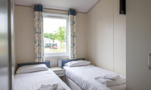 two beds in a small room with a window at Bude Holiday Resort by Away Resorts in Bude