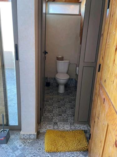 a bathroom with a toilet in a room with a door at Chez Manon & Said in Tamraght Ouzdar