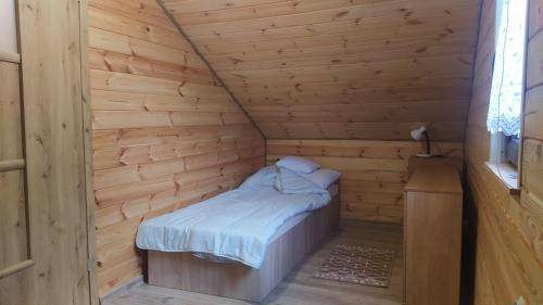a small room with a bed in a wooden cabin at Domki nad Wałpuszem in Stare Kiejkuty