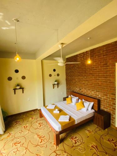 a bedroom with a bed with a brick wall at Lushy Glorious Hotel in Matara