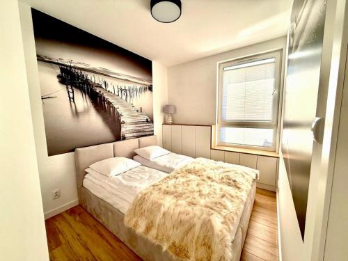 a bedroom with a bed and a painting of a pier at Jarzebinowa Loft by JumpInHere in Nowy Dwór Mazowiecki
