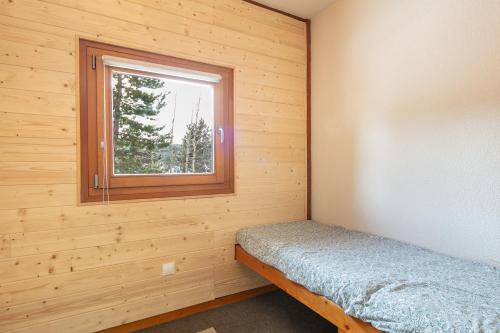 a small bedroom with a window in a wooden cabin at Le Martagon - Proche Station de Ski in Gresse-en-Vercors