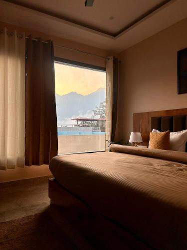a bedroom with a large window with a view of the ocean at Namaste Hostel Rishikesh in Rishīkesh