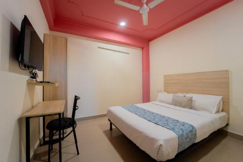a bedroom with a bed and a desk and a television at Capitol Square Near Railway Station in Jaipur