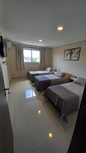 a room with four beds and a television in it at Carcano Temporarios in Villa Carlos Paz