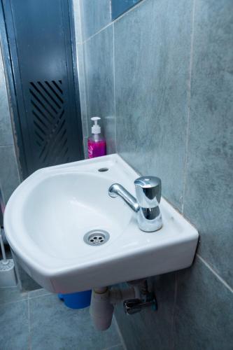 a white sink in a bathroom with a bottle of soap at comfystdkiambu in Kiambu