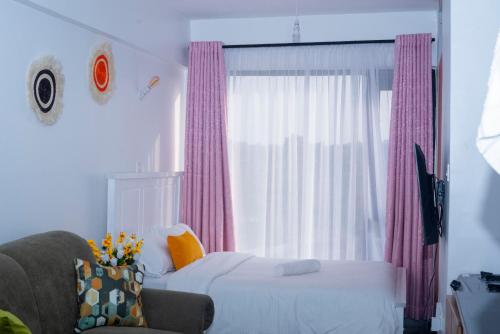 a bedroom with a bed and a chair and a window at comfystdkiambu in Kiambu