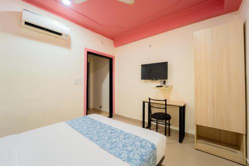 a bedroom with a bed and a desk and a television at Capitol Square Near Railway Station in Jaipur
