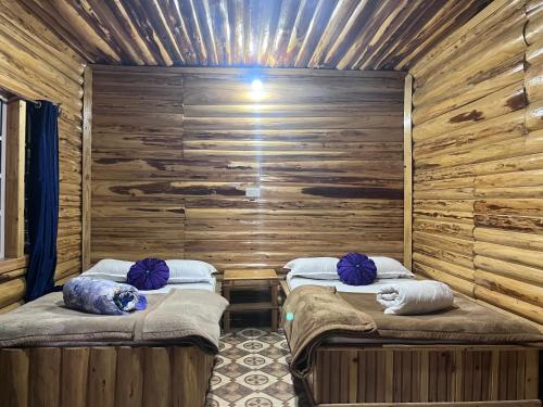 two twin beds in a room with wooden walls at Manjosila Homestay in Mirik