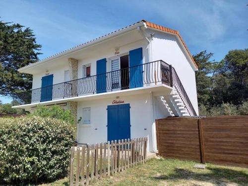 une maison blanche avec des portes bleues et une clôture dans l'établissement Christine, à Notre-Dame-de-Monts
