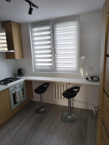 a kitchen with two bar stools in front of a window at Apartament w Biłgoraju in Biłgoraj