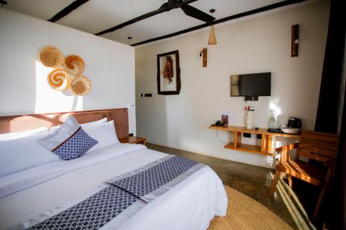 a bedroom with a bed and a desk and a tv at The Maridadi Hotel in Moshi