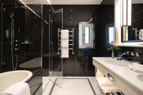 a black bathroom with a tub and a sink at Hotel Bellevue Palace Bern in Bern