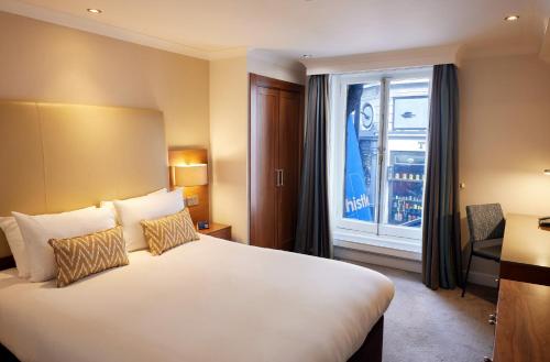 a hotel room with a large bed and a window at Thistle London Piccadilly in London