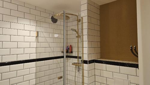 a shower in a bathroom with white tiles at Nieuwe Haven 23 in Dordrecht