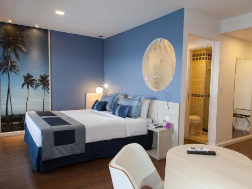 um quarto com uma cama grande e paredes azuis em Mercure Recife Navegantes em Recife