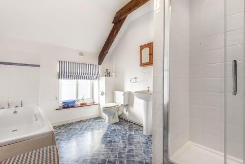 a bathroom with a tub and a toilet and a sink at Nelson Lodge in Burnham Market