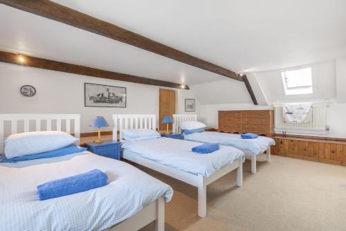 three beds in a room with white walls at Nelson Lodge in Burnham Market