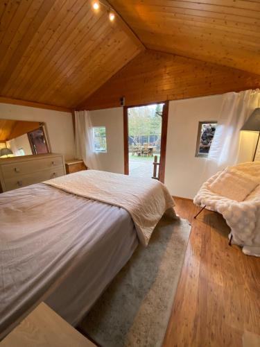 a bedroom with a large bed and a large window at Le Petit Chalet avec hottub. in Sint-Gillis-Waas