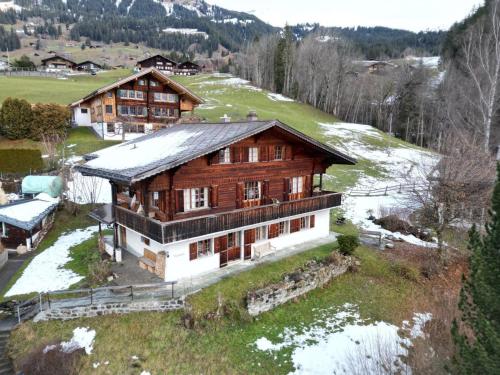 a large wooden house on top of a hill at Apartment Steirösli 1- & 2- Stock by Interhome in Lenk